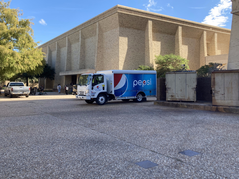 A Pepsi delivery truck, the colors clearly contrasted against the drab buildings in the background.