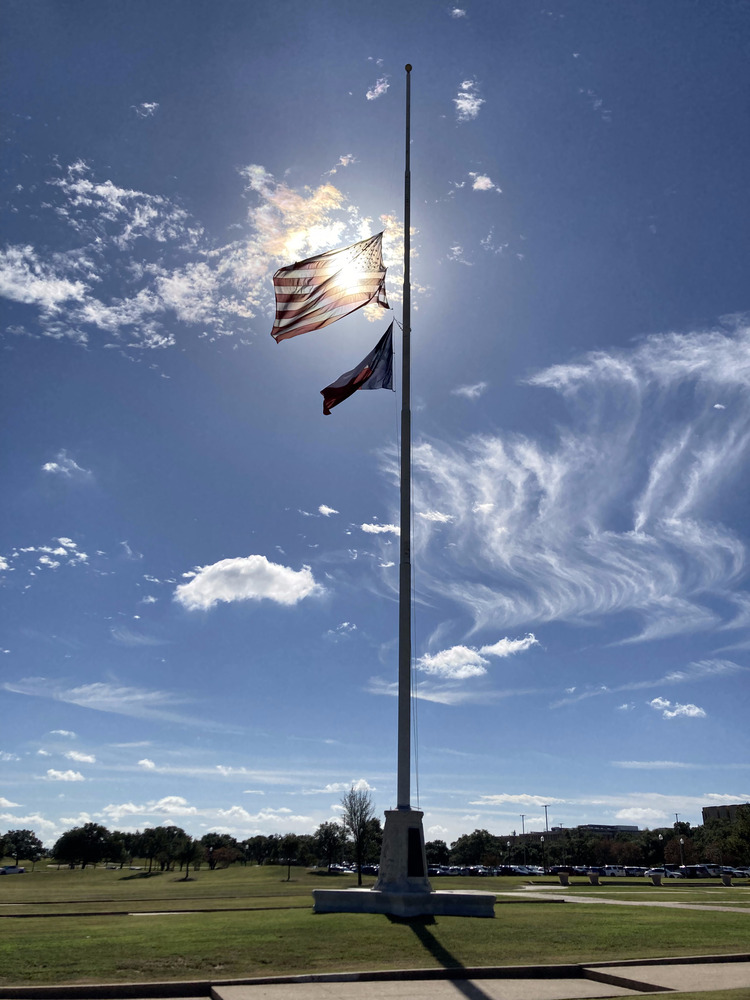 The same US and Texan flags, half mast, but with the US flag between the viewer and the sun, creating a neat eclipsed effect.