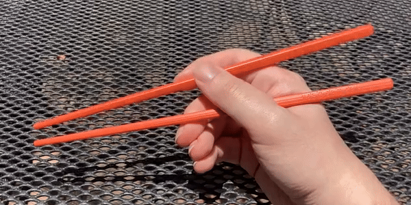 Moving the top chopstick with only my index finger, the thumb keeping it in place but not moving.